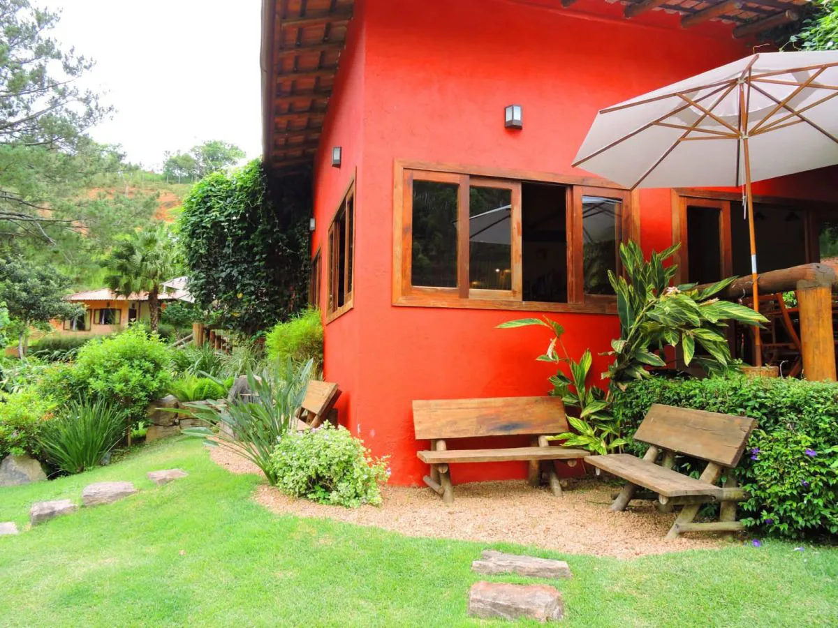 Chalé vermelho com bancos de madeira no jardim