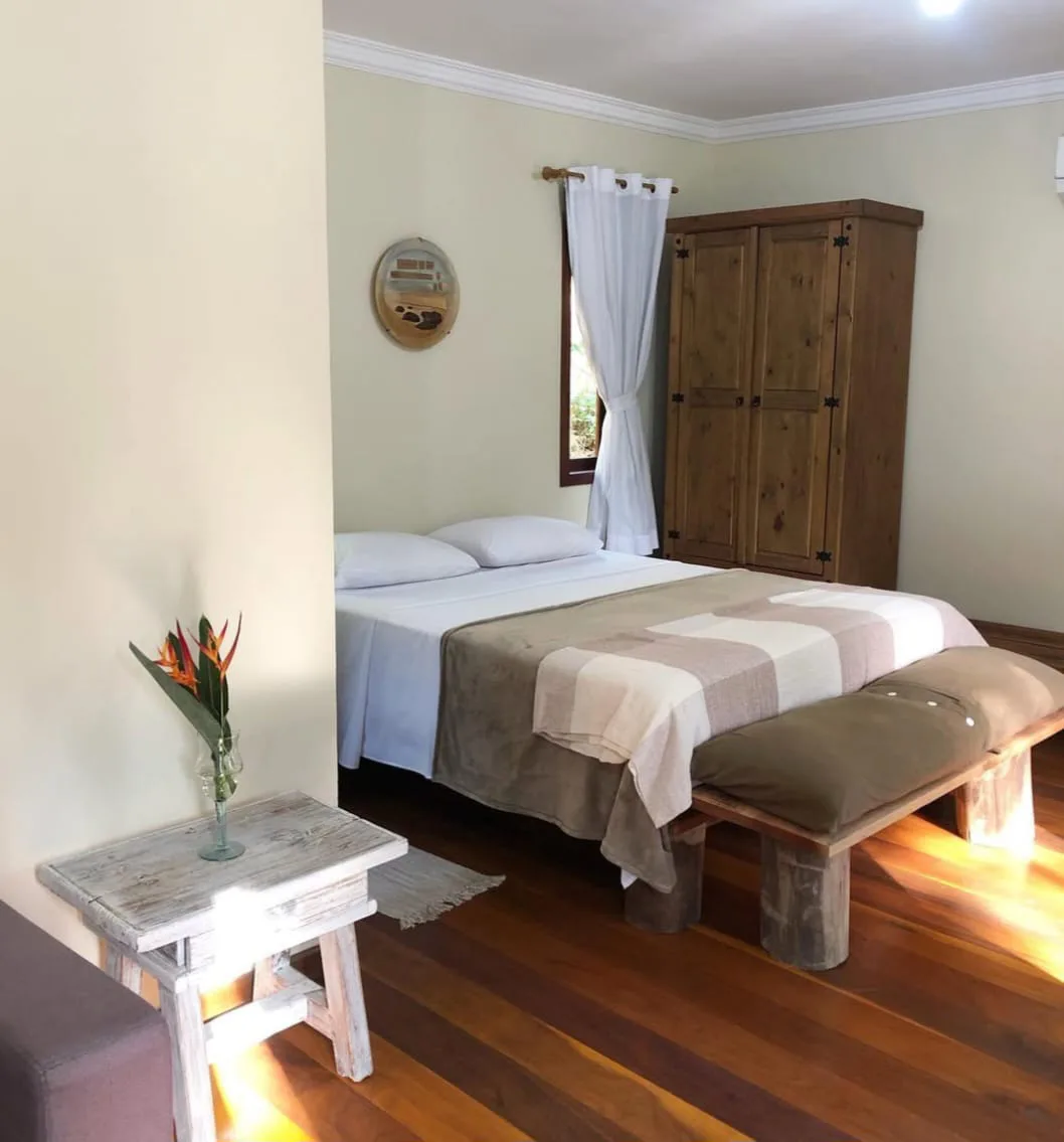 Suíte com cama de casal e baú de madeira
