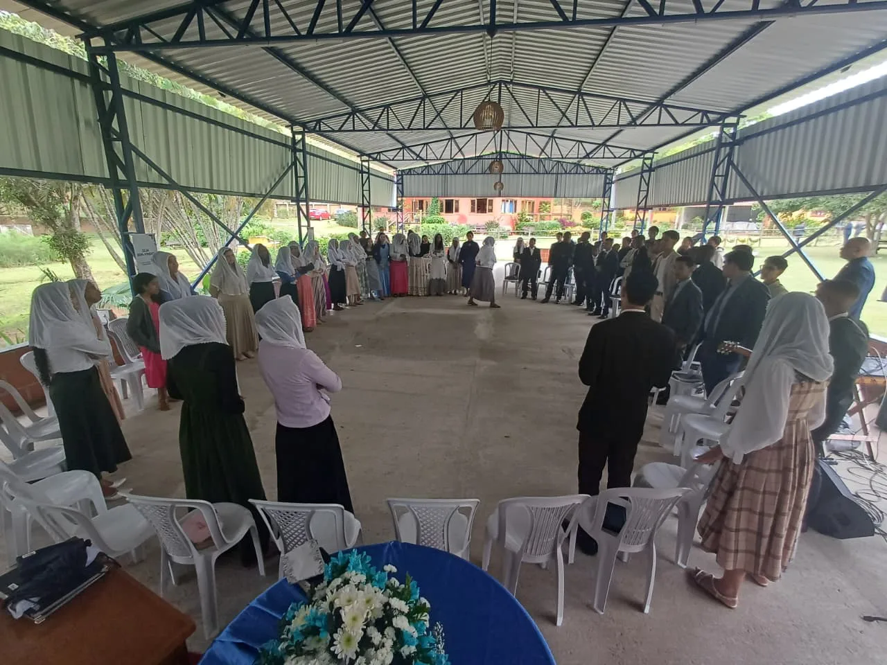 Irmãos reunidos no pavilhão coberto durante culto