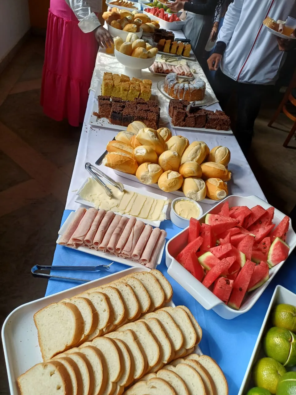Mesa de café com pães, bolos, frutas e frios