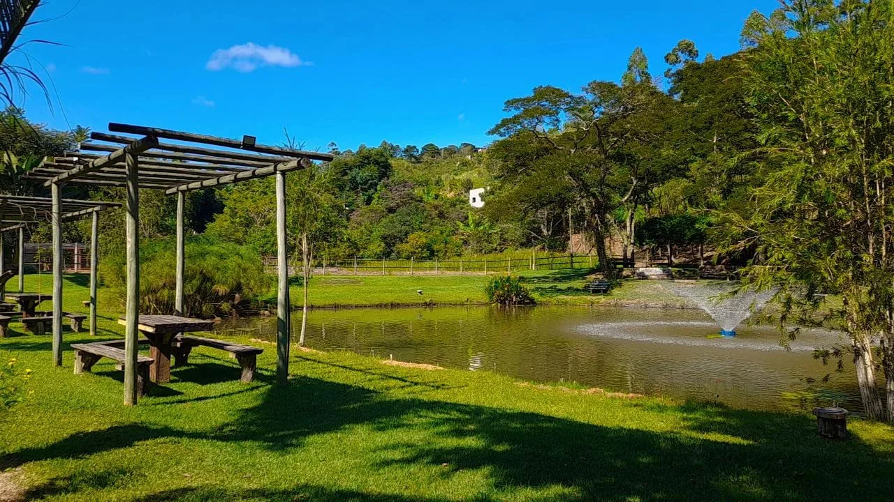 Lago com pérgola de madeira e montanhas ao fundo