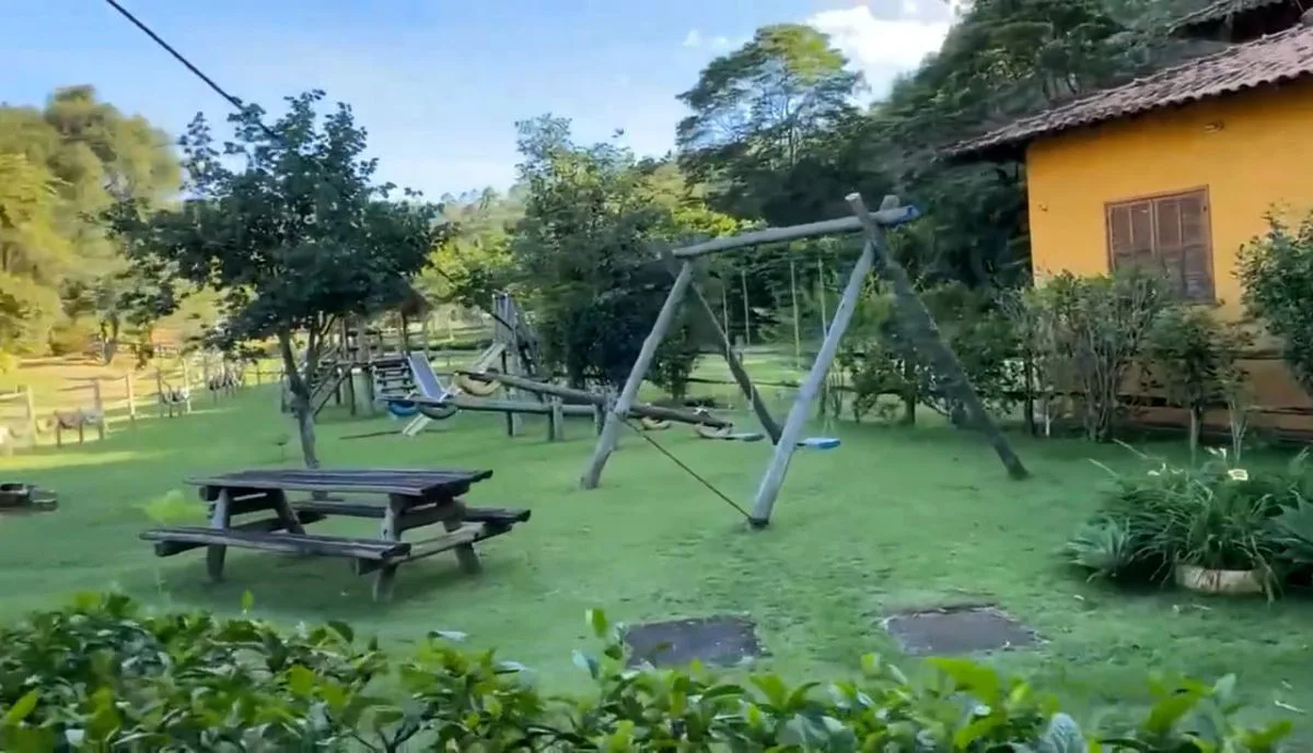 Parquinho com balanço de madeira e mesas de piquenique